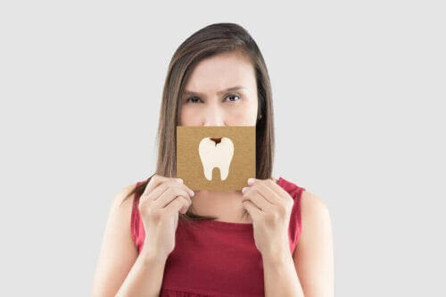 kvinna håller upp bild av kariesangripen tand