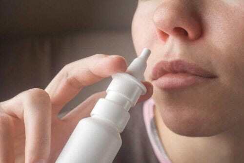 tar hand om en förkylning hemma: kvinna tar nässpray