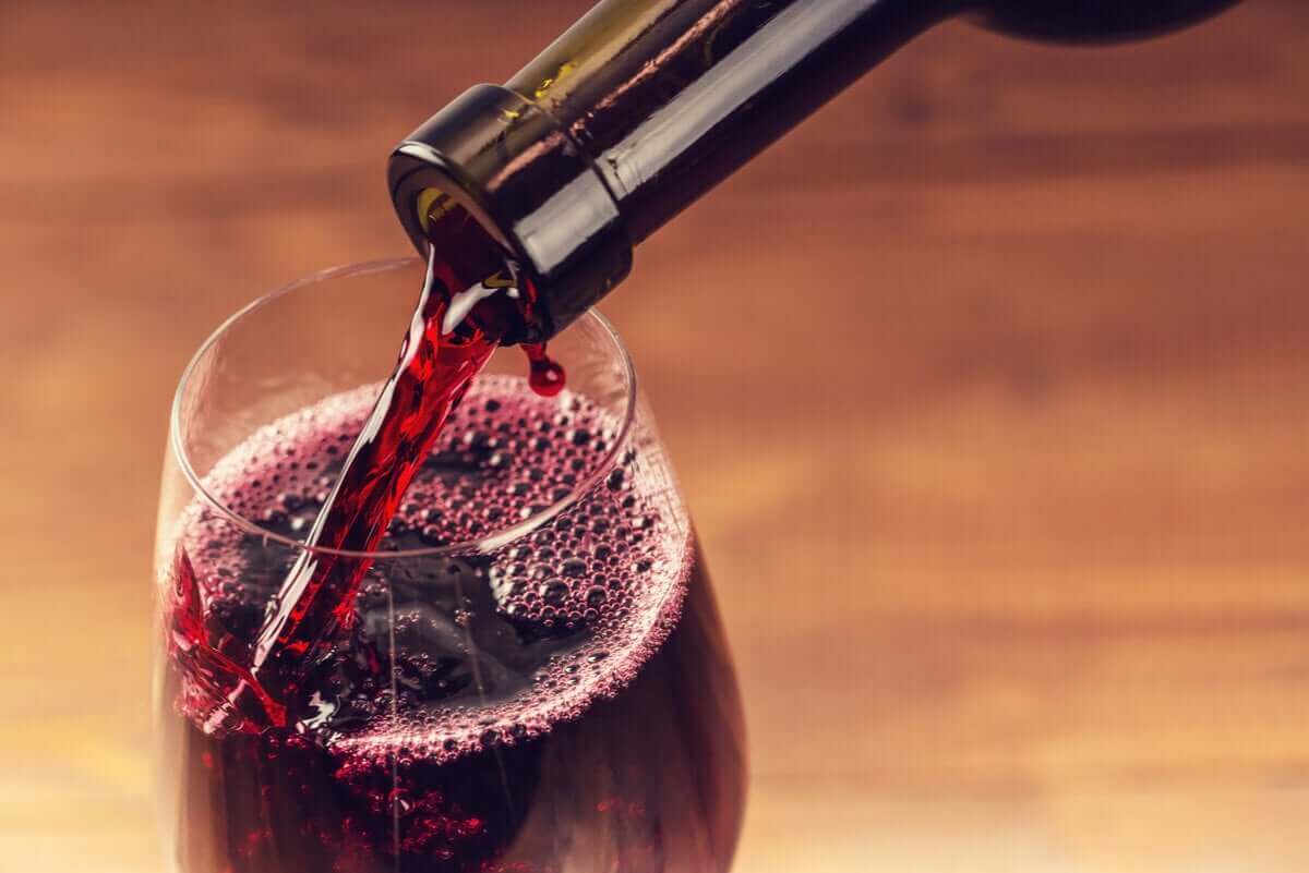 häller upp rött vin i glas