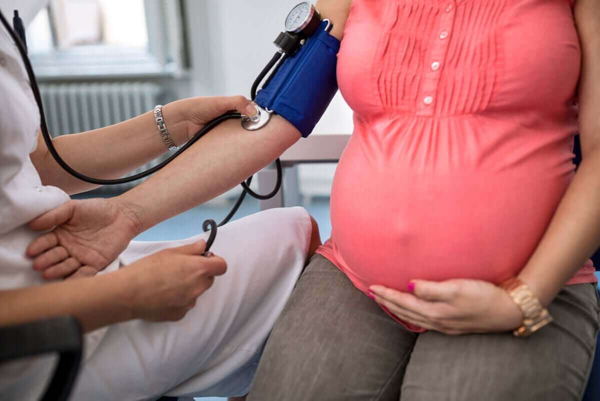 Fetma under graviditeten: läkare tar blodtryck på gravid kvinna