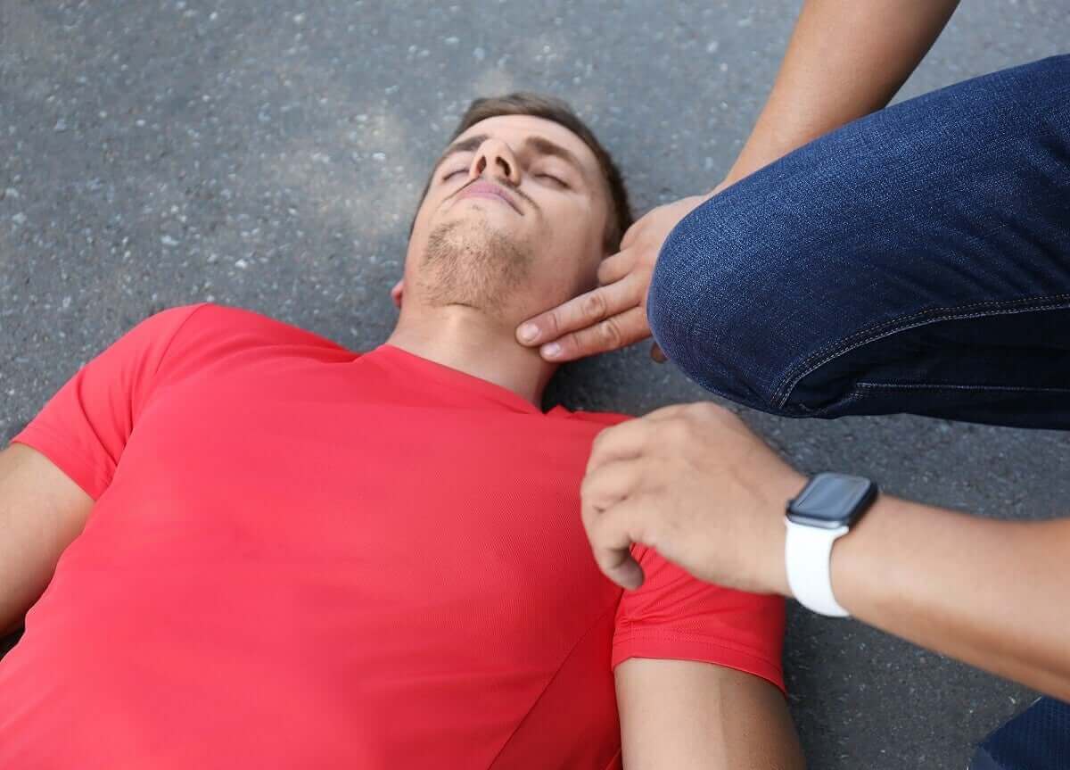 förhindra plötslig död: person tar pulsen på liggande man
