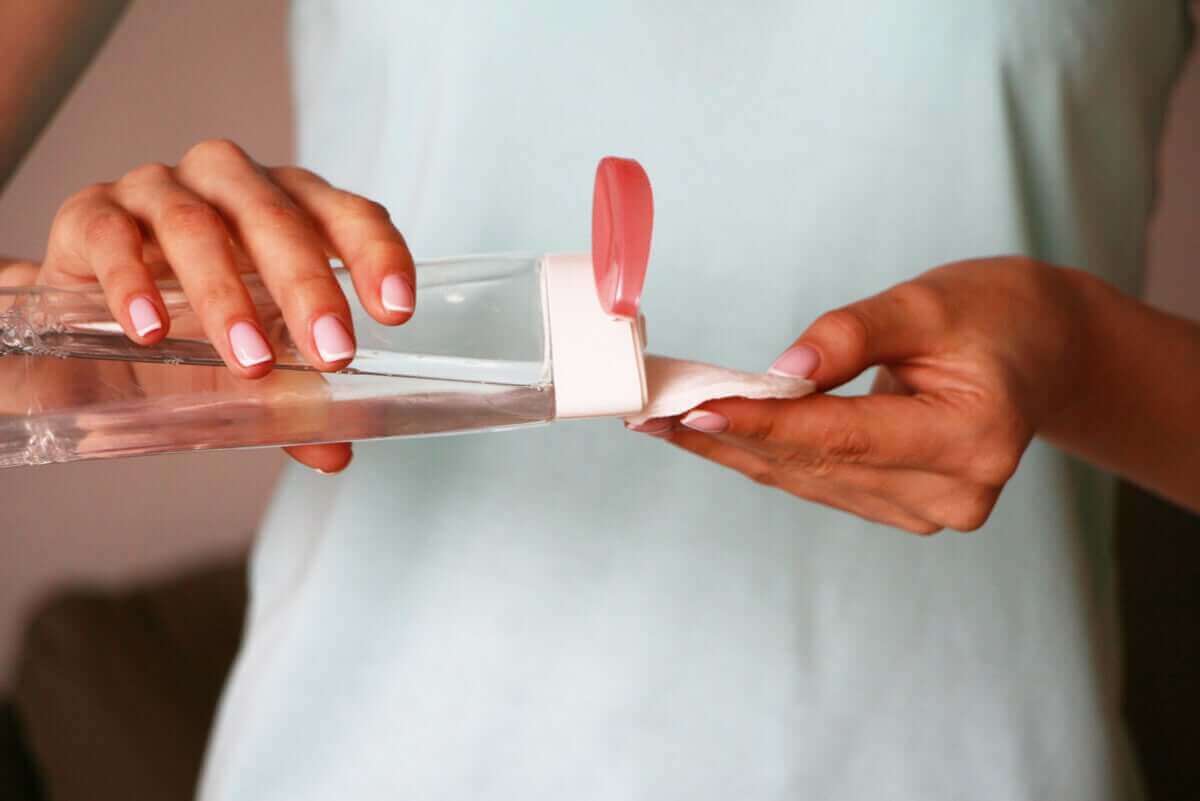 kvinna häller micellärt vatten på bomullstuss