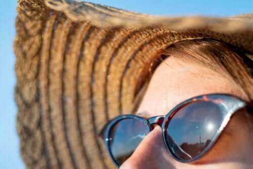 Hälsoeffekterna av solens strålar: kvinna i solhatt och solglasögon