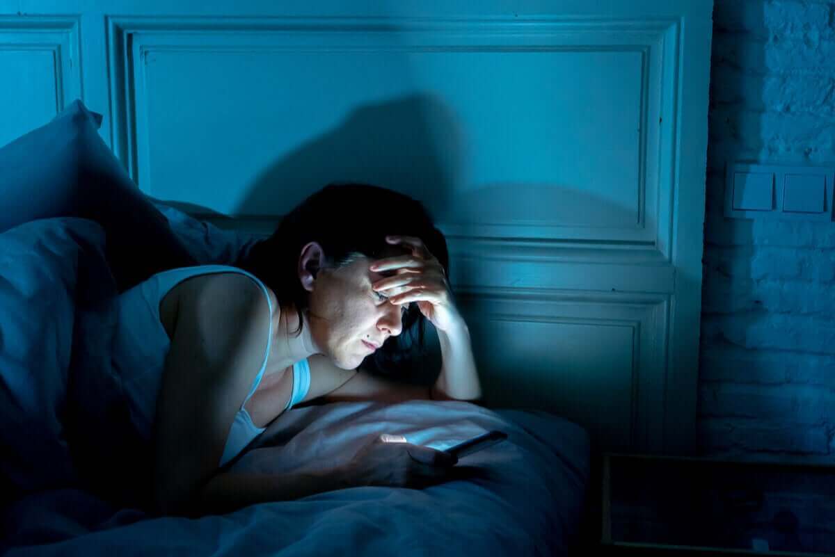 person tittar på mobil i sängen