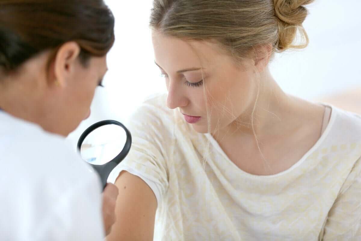 läkare undersöker kvinna för godartade hudtumörer