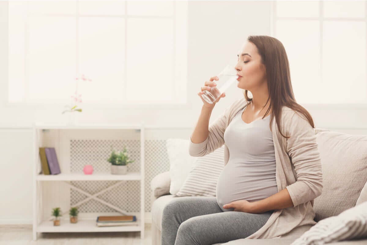 cystit under din graviditet: gravid kvinna dricker vatten