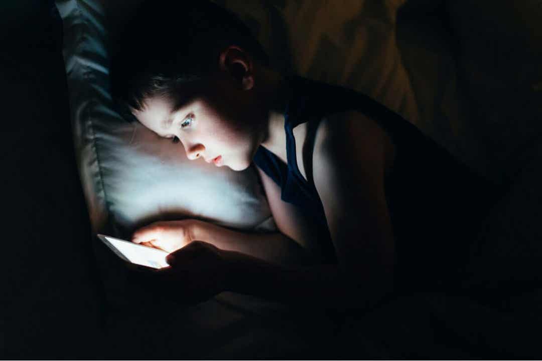 Sociala medier: barn tittar på mobil under täcket