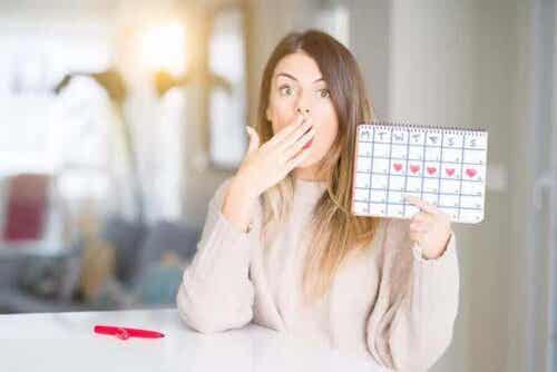 kvinna visar kalender med mensdagar utmärkta
