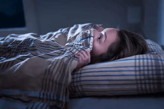 Kvinna i säng med generaliserat ångestsyndrom