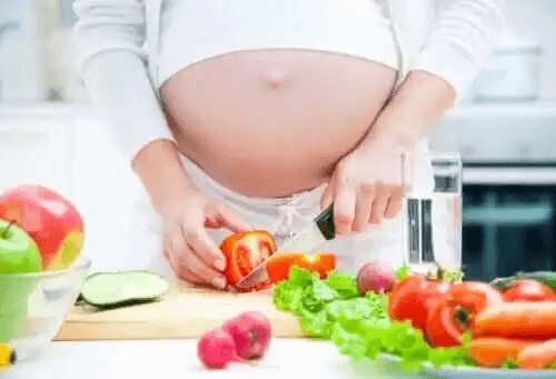 gravid kvinna skär upp grönsaker