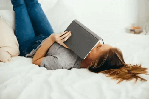 kvinna med bok i säng