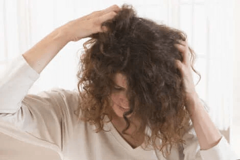 Håravfall under amningen: kvinna kliar sig i håret