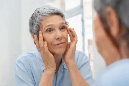 hälsosamt åldrande: vacker äldre kvinna ser sig i spegeln