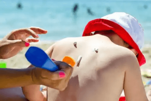 barn blir insmord med solkräm på ryggen