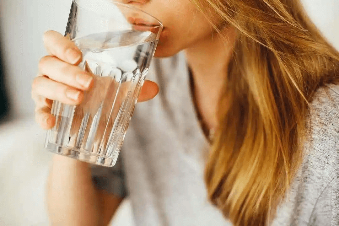 kvinna dricker ett stort glas vatten