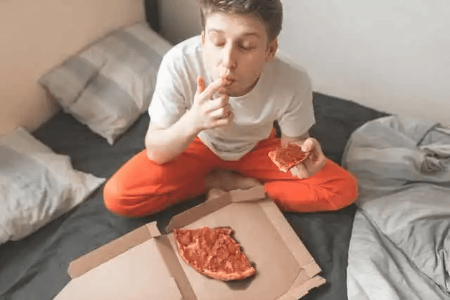 man äter pizza i säng
