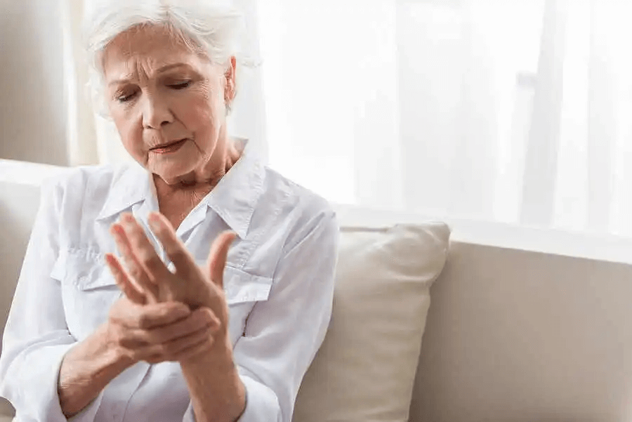 äldre kvinna masserar sin hand