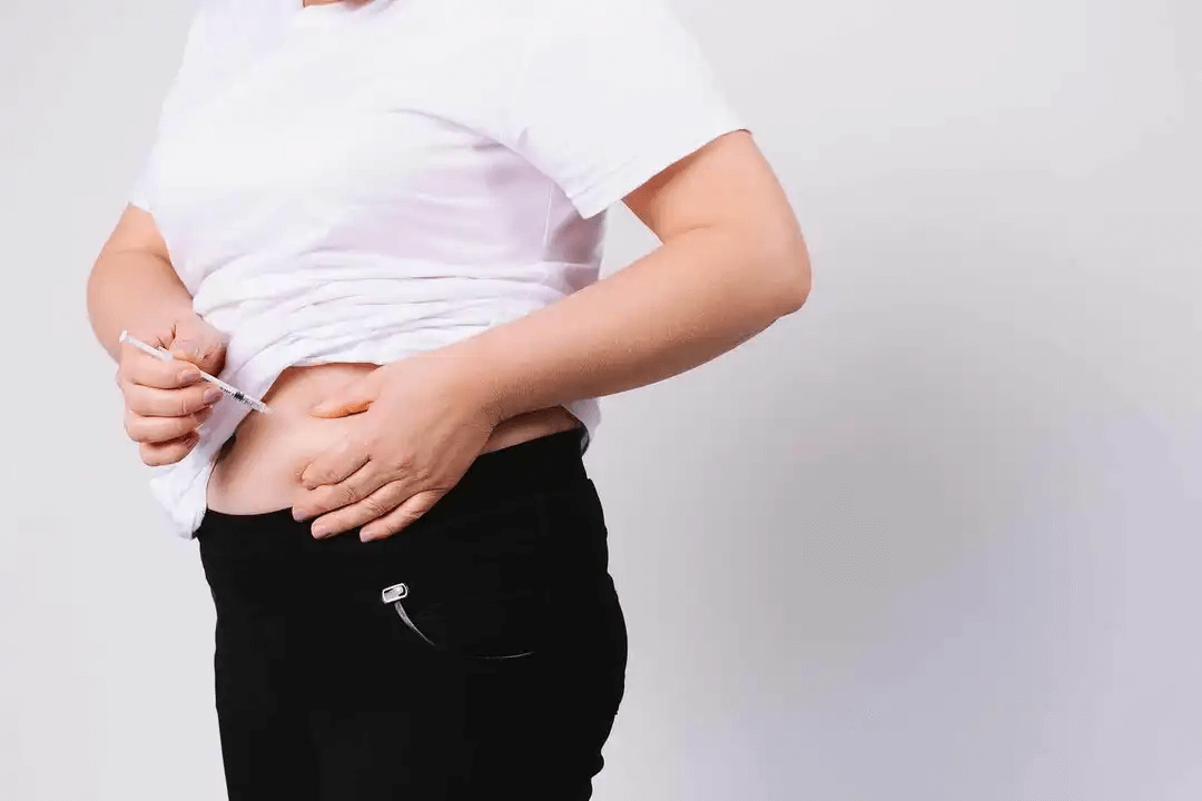 kvinna ger sig själv en subkutan injektion i magen