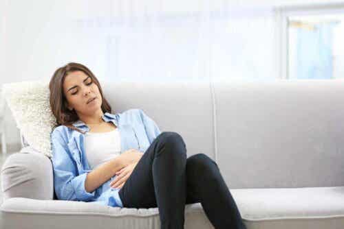 kvinna med ont i magen i soffa