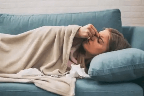 kvinna ligger på soffa och ser sjuk ut