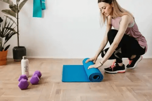 kvinna rullar ihop yogamatta