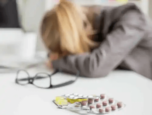mediciner orsakar huvudvärk hos kvinna på kontor