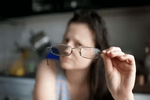 kvinna håller upp glasögon