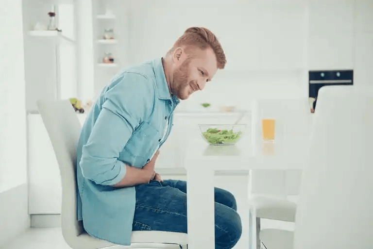 En man som äter sallad och har kramp i magen.