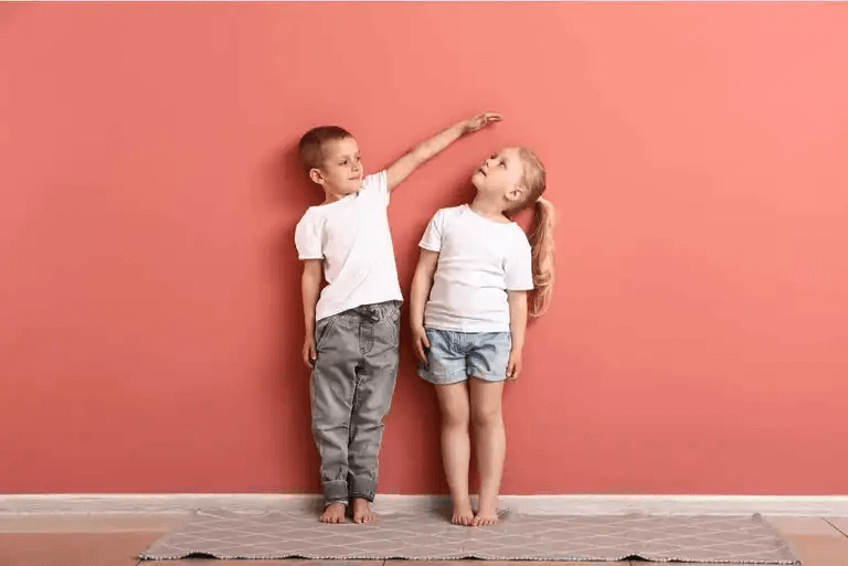pojke och flicka framför en rosa vägg som bråkar och leker