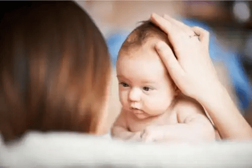 Mamma håller sin bebis huvud
