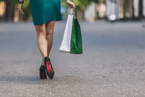 kvinna går i klackar med shoppingkassar