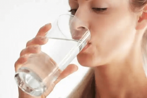 En kvinna som dricker ett glas vatten.