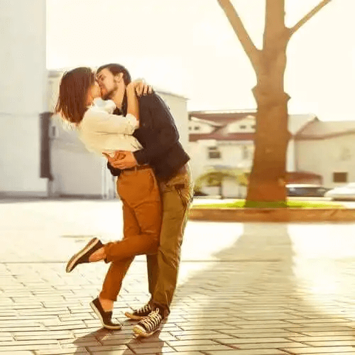 En kvinna lyfter sin fot i luften när hon kysser sin parther.