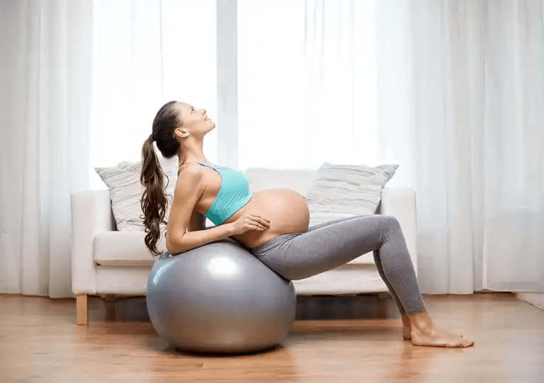 En gravid kvinna som använder en stor boll.