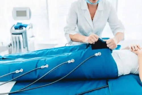 En professionell som använder pressoterapi på en patients underkropp.