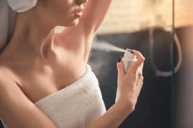 kvinna sprayar på en deodorant