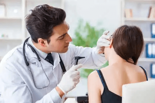 En läkare undersöker en kvinnas öra.