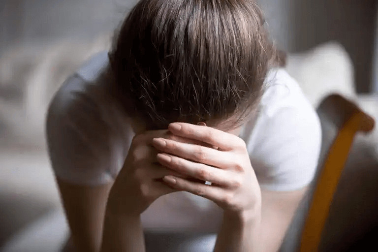 En kvinna med huvudet i händerna.