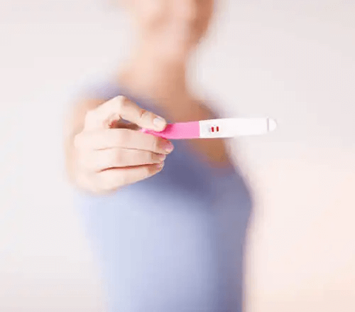 En kvinna som visar ett positivt graviditetstest.