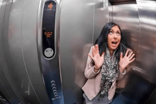 En kvinna får panik i en hiss pga rädslan för spindlar
