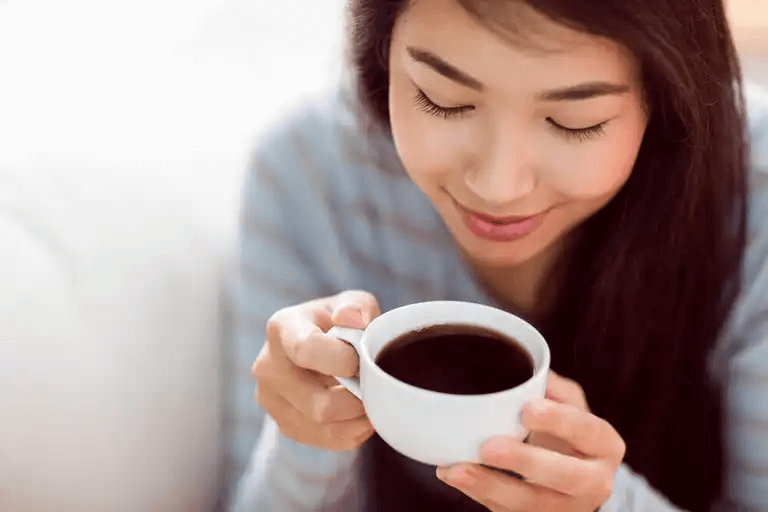 En kvinna som dricker en kopp kaffe.