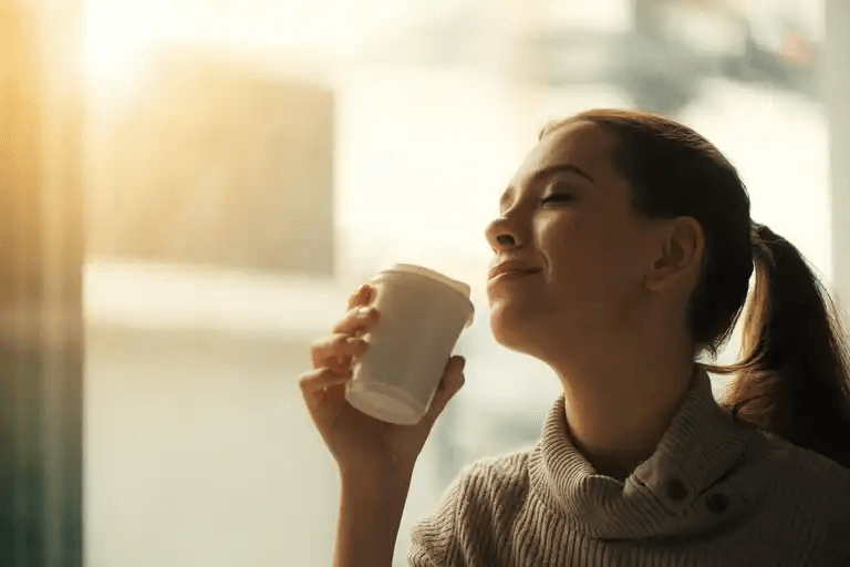 En kvinna som sitter på ett kafé och dricker kaffe.