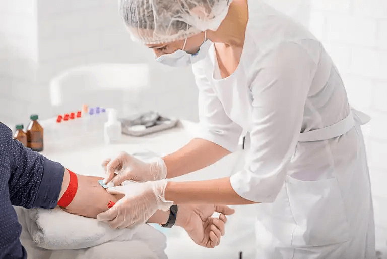 En sjuksköterska förbereder sig för att ta blod från en patients arm.