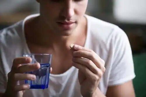 En person som håller ett piller och ett glas vatten.
