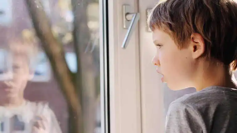 Barn med autism tittar ut genom fönster.