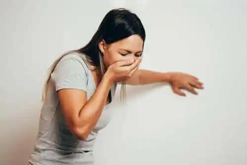 En kvinna som täcker sin mun med handen för att hon känner sig illamående.
