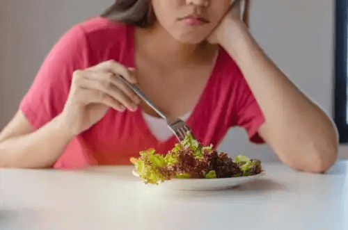 En kvinna som försöker äta en sallad.