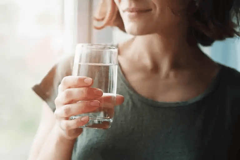 En kvinna som dricker ett glas vatten.