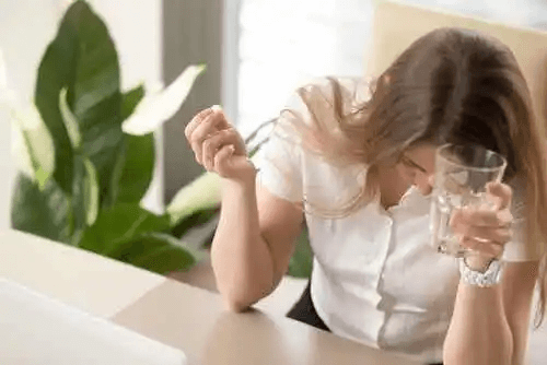 En kvinna som tar en dos av ett migränmedicin