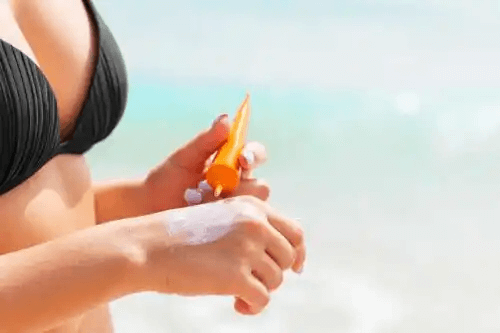 Kvinnan applicerar solskyddsmedel för att skydda mot UV-strålar